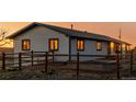 Detailed exterior of a single-story home featuring rustic wooden fencing and beautiful sunset light illuminating the windows at 35055 E Mississippi Ave, Watkins, CO 80137