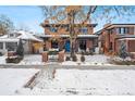 Charming two-story brick home featuring a landscaped yard with a black metal fence and walkway in a snowy landscape at 1131 S York St, Denver, CO 80210