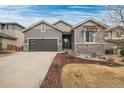 Charming home exterior featuring stone accents, a well-manicured lawn, and attached two car garage at 9382 Pike Way, Arvada, CO 80007