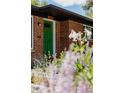 A green front door of a charming brick home with beautiful flowers in the front yard at 1695 S Beach Ct, Denver, CO 80219