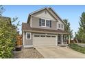 Attractive home with a beige two car garage, green lawn, mature trees, and covered porch with rocking chairs at 2115 Coach House Loop, Castle Rock, CO 80109