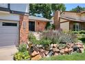 Inviting front entrance with brick facade, stone accents, vibrant flowers, and well-manicured landscaping at 12651 E Bates Cir, Aurora, CO 80014