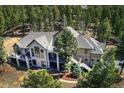 Expansive house exterior surrounded by trees, featuring a balcony and stairs at 26806 Evergreen Springs Rd, Evergreen, CO 80439