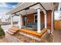 Charming front porch with brick steps, white pillars, and cozy outdoor furniture at 1614 Gaylord St, Denver, CO 80206