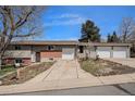 Split-level home showcasing attached garages, a brick facade, and a long driveway at 10983 W Exposition Pl, Lakewood, CO 80226