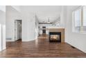 Bright, open-concept living room with a fireplace and hardwood floors adjoining a modern, white kitchen at 5241 S Shawnee St, Aurora, CO 80015