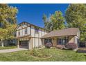 Beautifully landscaped front yard with a Tudor-style home featuring a two-car garage and swing at 10365 E Weaver Cir, Englewood, CO 80111