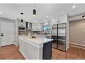 Modern kitchen boasts white cabinets, stainless steel appliances, a central island, and updated fixtures at 3802 E Costilla Ave, Centennial, CO 80122