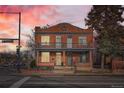 Charming brick two-story home with a balcony with pink sunset sky at 300 S Lincoln St, Denver, CO 80209