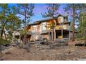 Multi-level deck on a beautiful home with a rocky backyard landscape, surrounded by mature trees at 30082 Troutdale Ridge Rd, Evergreen, CO 80439