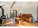 Bright living room with hardwood floors, wood beams, a fireplace, and comfortable seating under a ceiling fan at 268 Cedar Rd, Golden, CO 80401