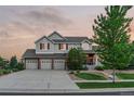 Beautiful two-story home with a three-car garage and lush landscaping, capturing a serene sunset view at 27290 E Nova Cir, Aurora, CO 80016
