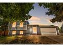 Charming gray two-story home with an attached garage against a twilight sky at 1705 Cathay Ct, Aurora, CO 80011
