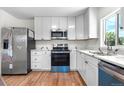 Bright kitchen featuring modern stainless steel appliances, white cabinets, and hardwood floors at 1705 Cathay Ct, Aurora, CO 80011