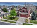 View of the two-story home with a two car garage and well-manicured lawn with mature tree at 22965 Allendale Ave, Parker, CO 80138