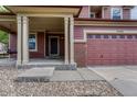 Inviting home entrance showcasing a covered front porch, well-kept lawn and brick detailing on a two car garage at 22965 Allendale Ave, Parker, CO 80138