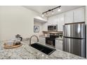 Modern kitchen with granite countertops, a black sink, stainless steel appliances, and sleek white cabinets at 2880 S Locust St # 704N, Denver, CO 80222