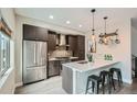 Contemporary kitchen featuring dark cabinets, stainless steel appliances, and a breakfast bar with seating for three at 2804 W 53Rd Ave, Denver, CO 80221