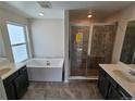 Elegant bathroom featuring a soaking tub, glass-enclosed shower, and double vanities with dark wood cabinets at 16654 W 93Rd Way, Arvada, CO 80007