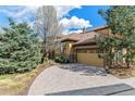 Charming home featuring a brick driveway, attached garage, and lush landscaping at 7850 Vallagio Ln, Englewood, CO 80112