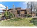 Charming stucco home with a tile roof, stone accents, manicured lawn, and mature trees at 7850 Vallagio Ln, Englewood, CO 80112