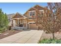 Charming two-story home with a covered front porch and a long driveway, framed by a colorful tree at 24416 E Powers Ave, Aurora, CO 80016