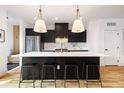 Modern kitchen featuring dark cabinetry, white marble backsplash, island with seating and pendant lighting at 2625 W 23Rd Ave, Denver, CO 80211