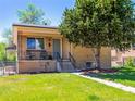 Inviting brick home with a cozy covered porch, manicured lawn, and mature tree for curb appeal at 2695 S Logan St, Denver, CO 80210