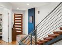 Bright, modern foyer featuring hardwood floors, statement staircase, and stylish wood door at 3841 Stuart St, Denver, CO 80212