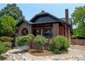 A charming brick home with a well-maintained front yard featuring mature trees and decorative stone accents at 2636 N Glencoe St, Denver, CO 80207