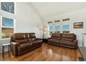 Bright living room with vaulted ceilings, hardwood floors, and comfortable leather sofas at 16651 Tree Haven St, Hudson, CO 80642