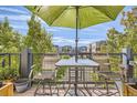 Outdoor patio with table, chairs, umbrella, and view of community buildings and greenery at 5401 S Park Terrace Ave # 301C, Greenwood Village, CO 80111