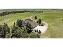 An aerial view showcasing the home, large driveway with basketball court, surrounding acreage, and mature trees at 36412 Paradise Cir, Elizabeth, CO 80107