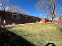 Spacious, fully fenced backyard with lush green grass, rock landscaping along house, and mature tree at 1662 S Everett St, Lakewood, CO 80232