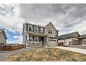 Charming two-story home with a covered front porch and attached two-car garage on a cloudy day at 935 Peach Leaf Ln, Elizabeth, CO 80107