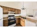 Functional kitchen with wooden cabinets, white appliances, and a vintage chandelier at 1100 S Waco St # D, Aurora, CO 80017