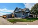 Inviting blue house with a covered porch, gravel landscaping, and a wood fence at 55490 E 27Th Pl, Strasburg, CO 80136