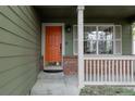 Inviting front porch with an orange door, brick trim, and large window at 11538 Hudson St, Thornton, CO 80233