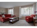 Bright living room with carpet, featuring large windows and red sofa and armchair at 11538 Hudson St, Thornton, CO 80233