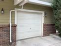 Attached one car garage door with brick siding and wall mounted lantern lighting at 11947 Riverstone Cir # 7F, Henderson, CO 80640