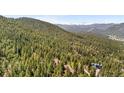 Aerial view showcases a wooded neighborhood surrounded by mountain scenery and blue skies at 4618 Se Summit Trl, Evergreen, CO 80439