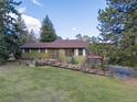 Inviting single Gathering home with a green exterior and red trim surrounded by mature trees and lush greenery at 8473 Gray Fox Dr, Evergreen, CO 80439