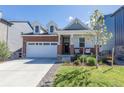 Charming home with brick accents, a covered front porch, and a well-maintained lawn under a clear sky at 9843 Rosalee Peak St, Littleton, CO 80125