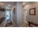 Long, neutral-toned hallway with wood-look flooring and wall art, leading to a brightly lit living area at 9843 Rosalee Peak St, Littleton, CO 80125