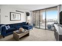 Bright living room featuring a comfortable blue sofa, neutral carpet, and large sliding glass doors at 1020 15Th St # 9N, Denver, CO 80202
