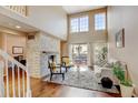 Bright living room features a soaring ceiling, large windows, and a stone fireplace at 9403 Southern Hills Cir, Lone Tree, CO 80124