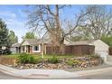 Landscaped yard with stone accents frames a brick home with a detached garage and wooden privacy fence at 1100 Pontiac St, Denver, CO 80220