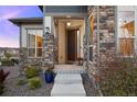 Inviting front porch with stone accents and colorful planters creating a welcoming entrance at 8505 S Tibet Ct, Aurora, CO 80016