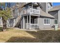 Gray townhome exterior with upper balcony, staircase, and well-maintained lawn at 8331 S Upham Way # 101, Littleton, CO 80128