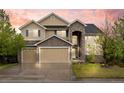Inviting two-story home featuring a stone archway, three-car garage, and mature landscaping at 5791 Chisholm Pl, Parker, CO 80134